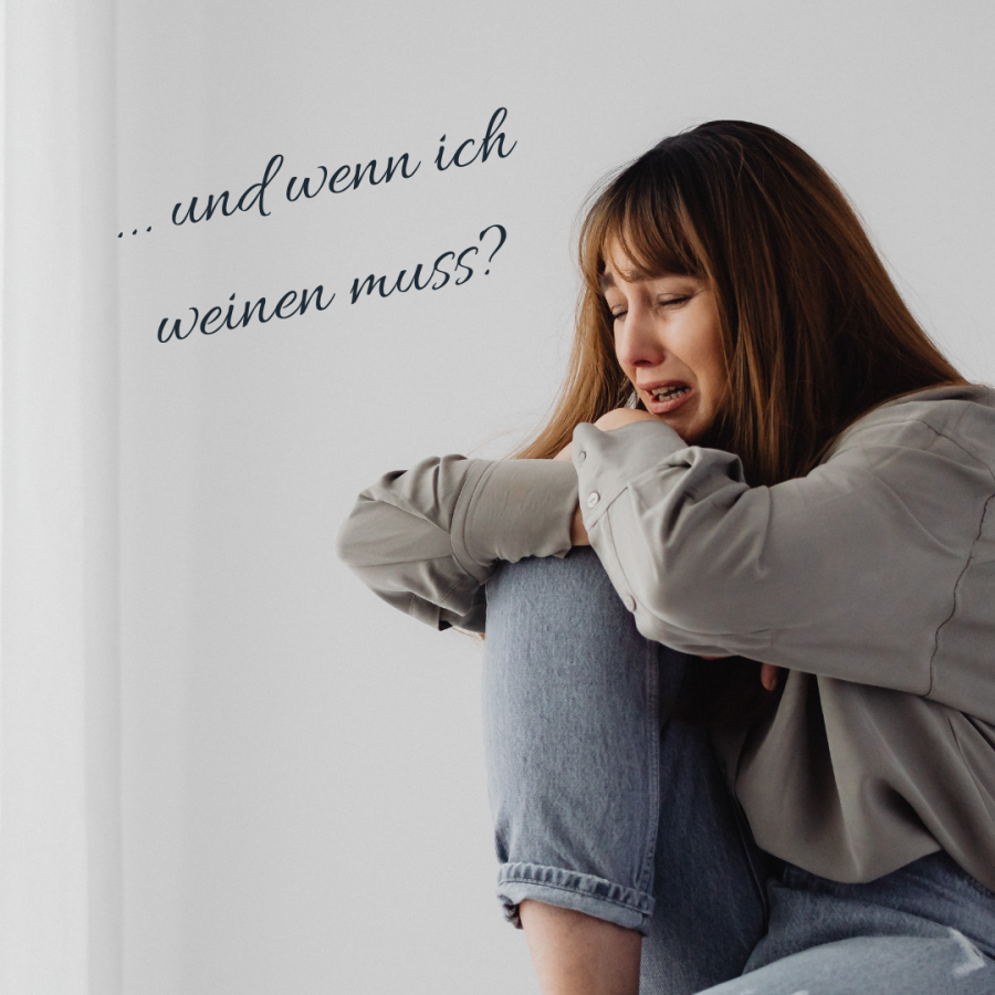 Weinende Frau, die mit angezogenen Knien vor einer hellen Wand sitzt, daneben der handgeschriebene Satz „… und wenn ich weinen muss?“