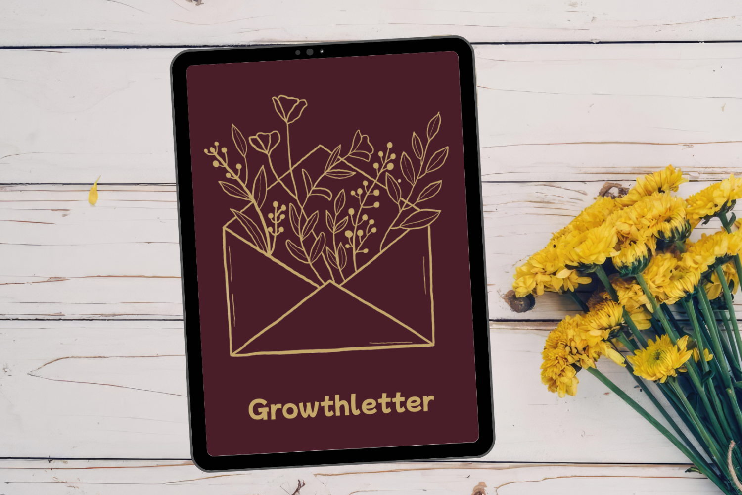 Tablet mit goldener Briefumschlag-Illustration, aus dem Blumen wachsen, und dem Schriftzug „Growthletter“, daneben gelbe Blumen auf einem weißen Holztisch.