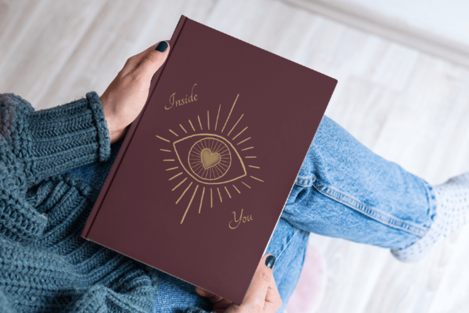 Person hält ein Buch zu „Inside You“ mit einer Illustration eines Auges mit Herz auf dem Cover.