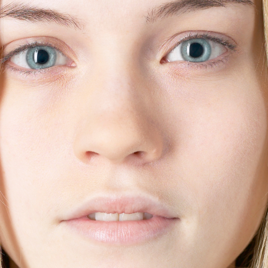Nahaufnahme eines Gesichts mit heller, feinporiger Haut und blauen Augen
