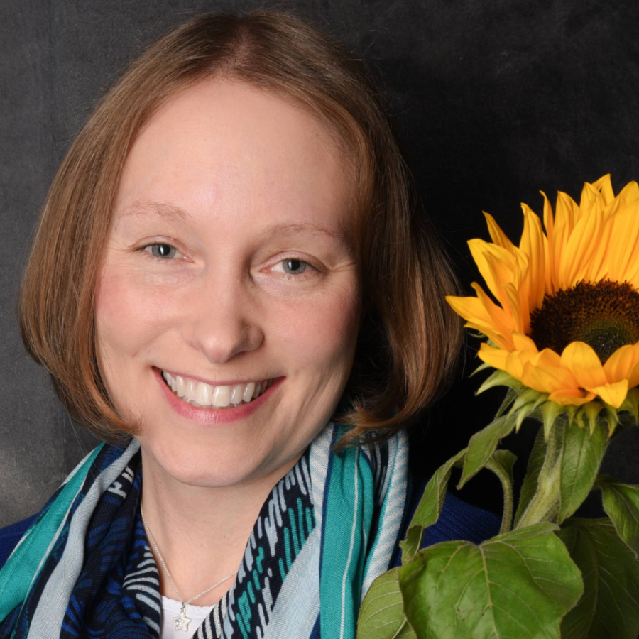 Porträt von Coach Carina mit einer Sonnenblume als Symbol für ihre Begleitung auf dem Weg zu persönlichem Wachstum und mehr Lebenszufriedenheit.
