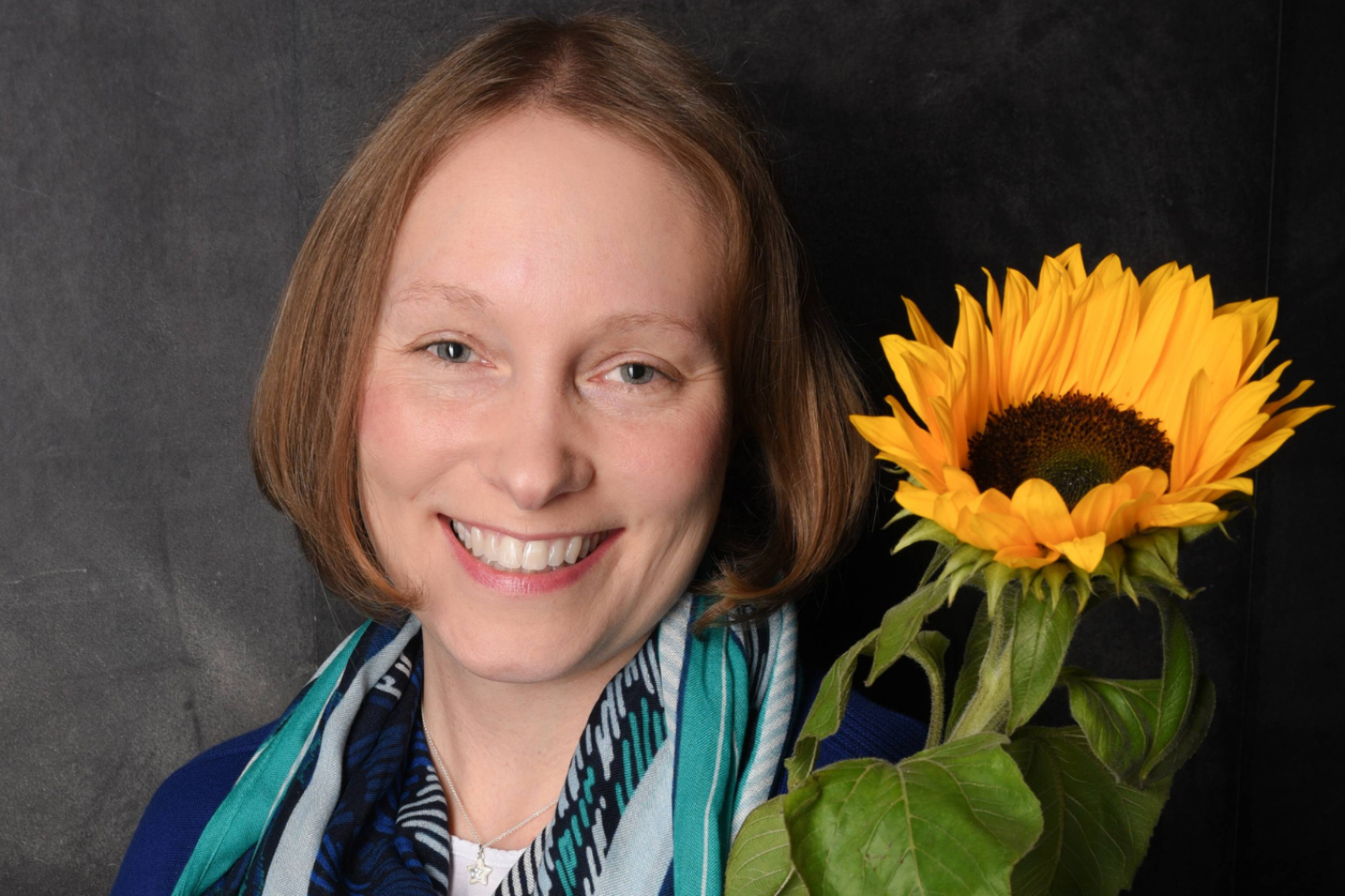 Porträt von Coach Carina mit einer Sonnenblume als Symbol für ihre Begleitung auf dem Weg zu persönlichem Wachstum und mehr Lebenszufriedenheit.